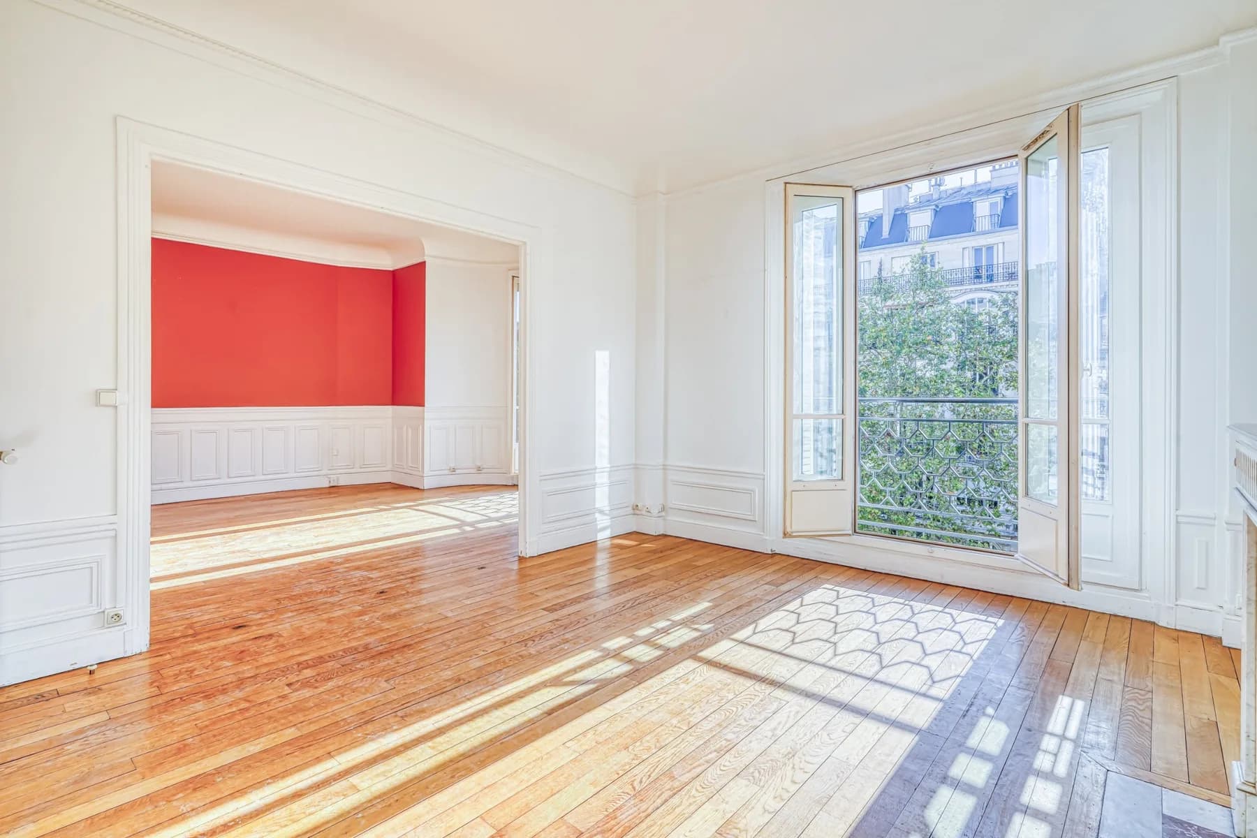 Salon lumineux, moulures et porte-fenêtre ouvrant sur les arbres de l'avenue