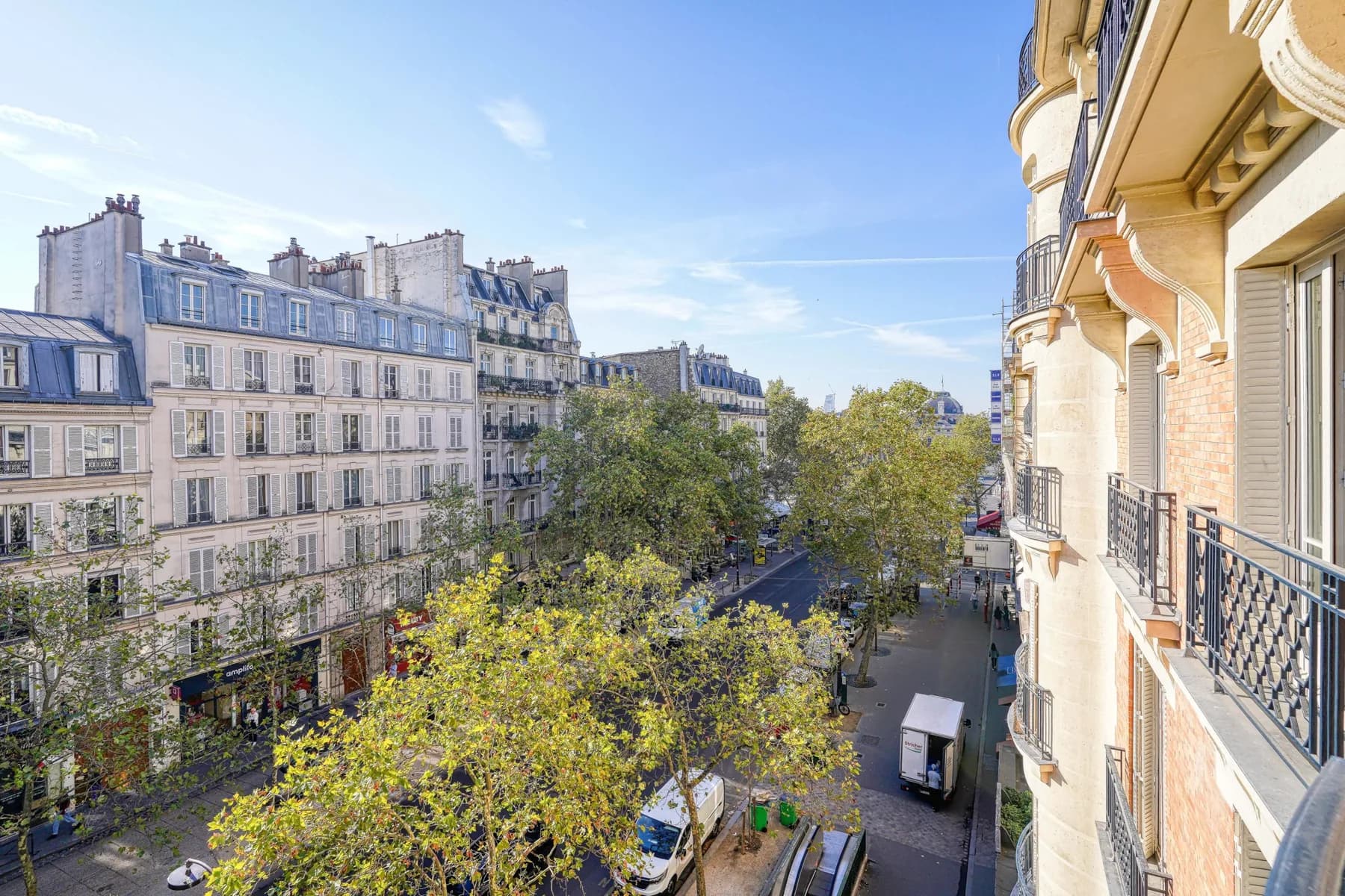 Vue depuis le balcon sur l'avenue arborée et les toits parisiens